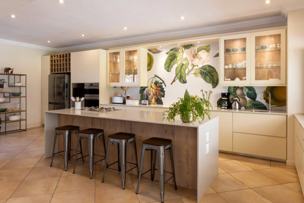 This kitchen brings the outdoors in with a stunning botanical wallpaper that adds life and colour to the space. The soft, creamy cabinetry and natural wood accents create a warm, inviting ambience that’s both modern and timeless.